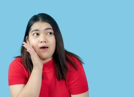 Portrait girl young woman asian chubby fat cute beautiful pretty one person wearing a red shirt is sitting smiling enjoy happily looking wow to copyspace imaginary on the blue background photo