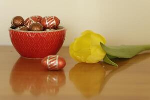 bowl with chocolate easter eggs and yellow tulip photo