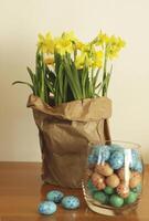 paper bag with daffodils and easter eggs photo