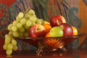 Fruta cuenco con uvas, manzanas, naranjas foto