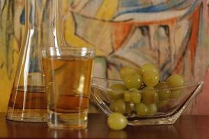 a glass of apple juice and a bowl with grapes photo