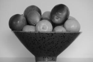 a bowl with mixed fruit in black and white photo