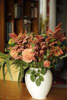 a white vase with a bouquet salmon color flowers photo