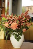 a white vase with a bouquet salmon color flowers photo