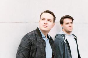 two male teenage friends or brothers leaning against wall photo