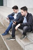 dos móvil teléfono fanático masculino adolescentes mirando a teléfono inteligente foto