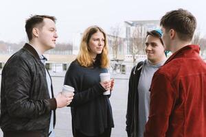 group of teenage friends having a conversation while standing together on city street photo