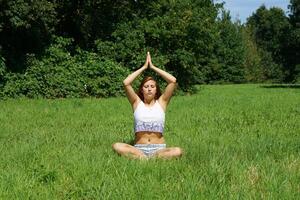 young woman practicing yoga meditation outdoors photo