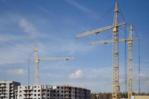 urbano construcción de edificios, grúas en el antecedentes de el cielo foto