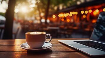 A laptop is lying on the table, there is a cup of coffee next to it photo