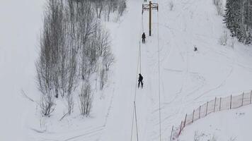 Ski lift rope tow snowy ski resort rope tow in winter forest setting aerial view. Ski lift rope tow winter northern nature resort relaxation unexplored north natural beauty white snow cold climate. video