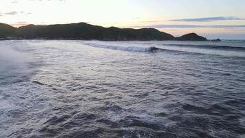 furioso mar en el Mañana a amanecer olas rodar en el rocoso apuntalar rociar se eleva dentro el cielo video