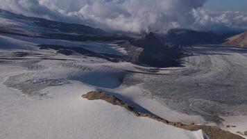 aérien vue glacier sculpte par montagnes la terre chef-d'oeuvre glacier dans hiver paysage havre pour tranquillité nord esthétique. au milieu de des nuages glacier révèle la terre robuste intacte beauté. video