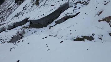 através Nevado clima Câmera varre sobre rochoso terreno aéreo topo Visão rochoso terreno resumo do intocado majestoso natureza. rochoso terreno gelado país das maravilhas às esqui resorts espírito norte sussurros dentro vento. video