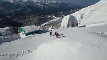 Aerial. skiers walk along the road at the top of the ridge paved by snowcat video