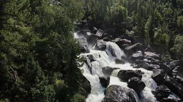 Aerial view of the cascading Uchar waterfall, flowing over rocks and forests video