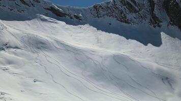 antenne. een skiër gaat naar beneden de helling Aan vers sneeuw in reusachtig bergen video