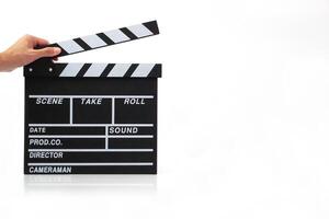 Hand holding a clapperboard or movie slate black color on white background. Cinema industry, production and film concept. photo