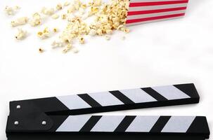 Clapperboard or movie slate black color with popcorn on white background. Cinema industry, production and film concept. photo