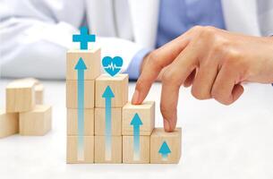 Two fingers of doctor is walking up stairs wooden blocks with medical symbol icons. Concept of Success, progress and growth. photo