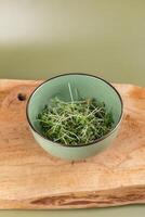 Microgreens in a deep bowl on the board. Ingredient for cooking. Useful food for immunity photo