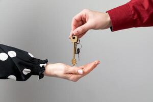 Female hand holding key and handing it over to another person. photo