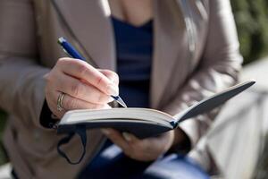 The woman holds up a notepad and pen. She is making notes in her weekly book photo