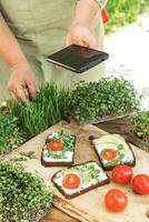 Woman photographing sandwiches with microgreens photo