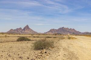 Panoramic picture of the Spitzkoppe in Namibia during the day against a blue sky photo