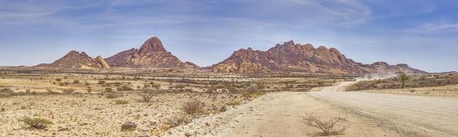 Panoramic picture of the Spitzkoppe in Namibia during the day against a blue sky photo