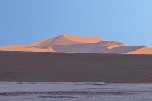 panorámico imagen de el rojo dunas de el namib Desierto en Namibia en contra un azul cielo en el noche ligero foto