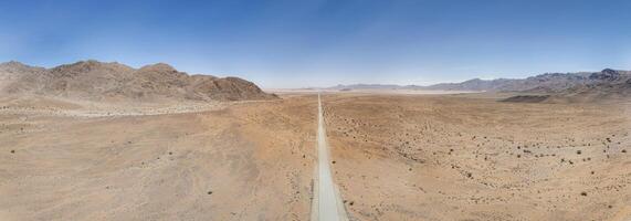 Panoramic drone picture of a lonely gravel road through the desert photo