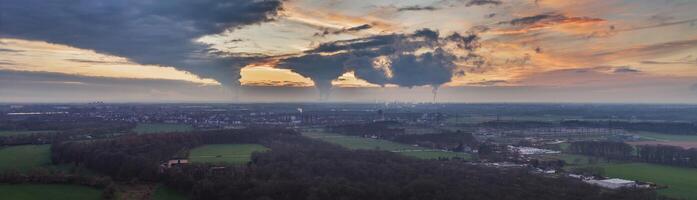 Drone image of the evening sky of the German industrial region of the Ruhr with several chimneys emitting large quantities of exhaust fumes photo