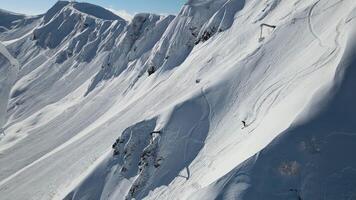 esquiador desciende Nevado Pendiente entre majestuoso montañas esquiador abrazando frío de del norte naturaleza. esquiador símbolo de de invierno intacto belleza y esquí ocio danza con invierno viaje mediante nieve. video