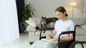 Jeune femme séance sur le fauteuil roulant en train de lire une livre à Accueil video