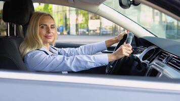 Portrait of a confident 50 years woman sitting in a car in a business suit near a modern office building video