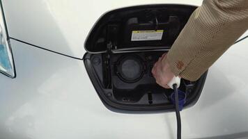 Unrecognizable senior man disconnects charging cable to electric vehicle. Male hand unplugs power connector into EV car and charges batteries video