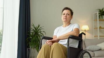 Portrait of mature sad woman sitting in wheelchair at home and looking at camera video