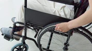 Close-up of woman's hand moving wheelchair indoors at home. Young woman is busy with domestic activities video
