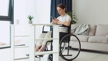 motivado trabalhador autonomo usa Smartphone sentado dentro cadeira de rodas às lar. distante trabalhos conceito video
