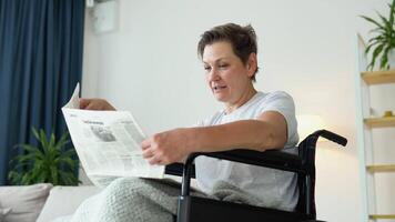 Senior Frau Sitzung im ein Rollstuhl und lesen ein Zeitung beim Zuhause video