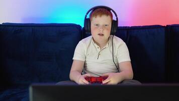 Gamer discussing tactics with teammates while talking into headset. A boy gamer is sitting on a couch, playing and winning in games on console video