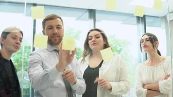 Young corporation employees are discussing a business plan with stickers in the office video