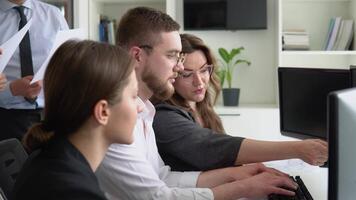 A group of young male and female office employees sitting and discussing on a project in a conference or board room meeting video