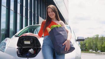 Woman standing by the electric car with groceries. Environmental and eco-friendly technologies. Renewable concept video