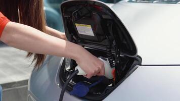 Girl starts charging her electric car. Charging electro car at the electric gas station video