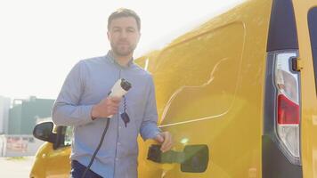 A man with a charger at a charging station looks into the camera video