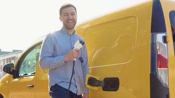 A happy man with a charger at a charging station video