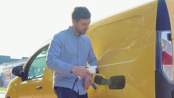 A man plugging in charging cable to to electric vehicle and charges batteries. Male hand inserts power connector into EV car video