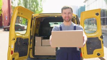 Porträt von ein Kurier halten ein Paket, ein Gelb Auto im das Hintergrund. das Kurier liefert das Paket und Hand es zu das Klient video